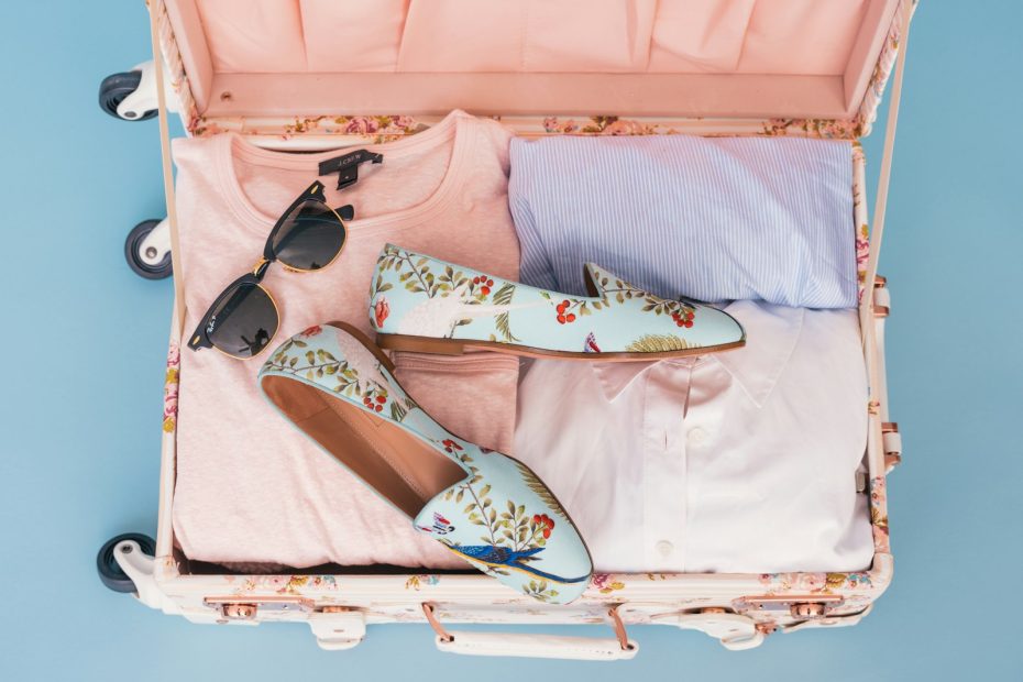 An open suitcase with neatly packed clothes, shoes and sunglasses