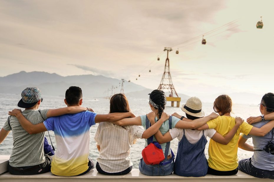 A group of friends sitting on a wall with their arms around each other