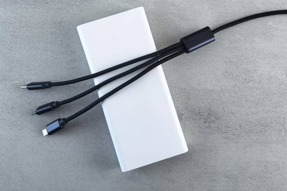 A white power bank with several charging cables