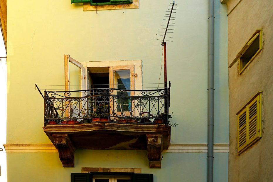 A small iron balcony on a pastel-colored building