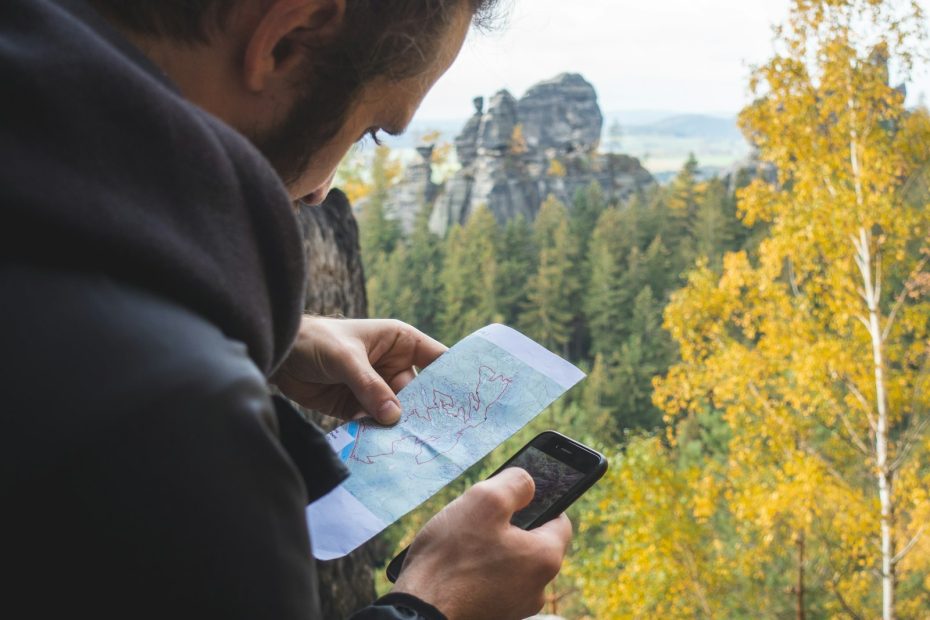 A traveler checking a phone and a paper map outdoors